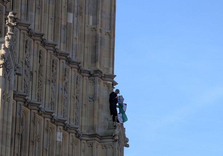 Un hombre se encarama a la torre del Big Ben enarbolando la bandera palestina